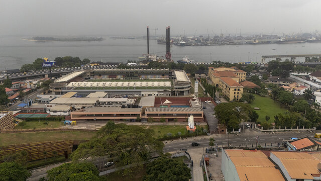 Aerial view of the Mobolaji Johnson Arena stadium on Lagos Island, featuring the green pitch, urban infrastructure, and the waterfront with industrial vessels in Lagos, Lagos, Nigeria.