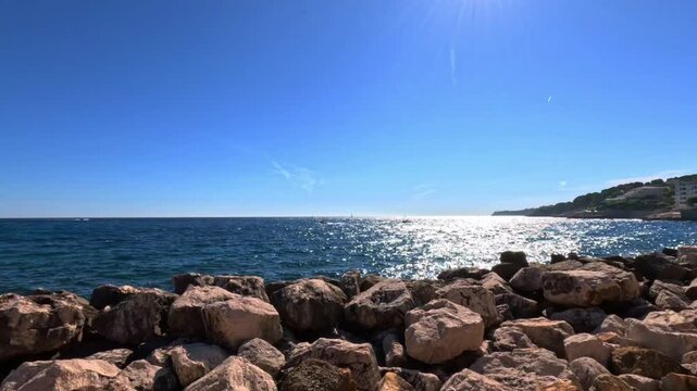 Sparkling blue sea of Cassis on a sunny day, French Riviera, Provence-Alpes-C&ocirc;te d'Azur, France, Europe. Sun reflecting on the sea behind a rocky breakwater in Cassis, Bouches-du-Rh&ocirc;ne, France, Europe