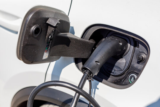 Close-up of an electric vehicle (EV) being charged with a cable, symbolizing green energy.