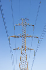 Obraz premium Electric power transmission pylon against a clear blue sky