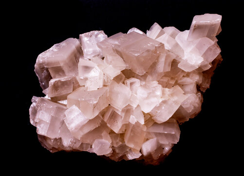 Close-up studio shot of a raw cubic calcite mineral specimen, featuring translucent white crystal formations against a stark black background.