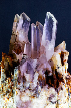 Macro photograph of natural quartz crystals rising from an earthy matrix, capturing brilliant facets and intricate geological formations under studio lights.