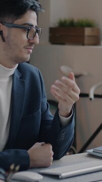Middle Eastern businessman speaking to partner during online video call using computer and earphones in office. Communication and business concept.