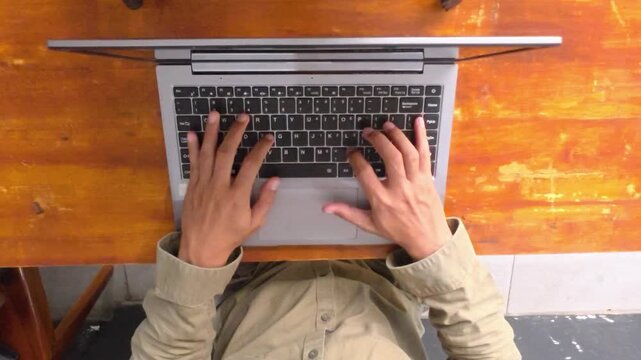 Top View Of Hands Typing On Laptop Keyboard