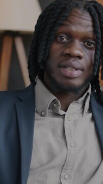 Portrait of African American entrepreneur speaking looking at camera showing business document during online video call from office. Communication and virtual meeting concept.