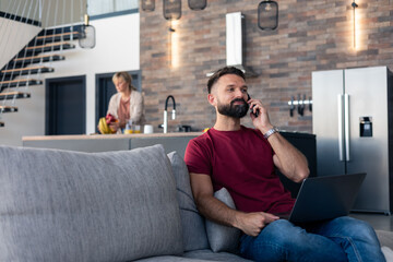 Fototapeta premium Man working remotely from home living room having phone call