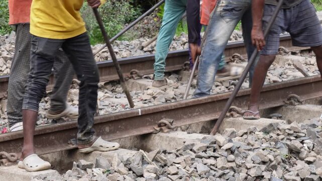 Railway workers performing track maintenance and rail alignment