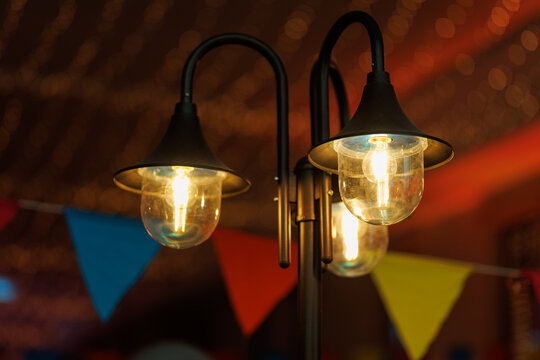 Black lantern post with illuminated glass lamps and colorful flags