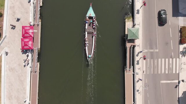 Drone: Aerial View of a Traditional Moliceiro Boat Navigating a Canal in Aveiro, Portugal