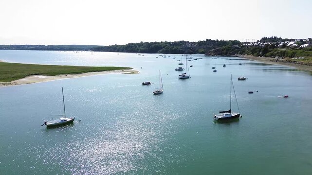 Aerial landscape footage of the Rance estuary in Brittany, showing Pont Saint-Hubert, anchored sailboats and the residential landscape of Saint-Jean along the wooded shoreline.
