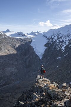 Mountaineer standing on a rock, surrounded by an impressive mountain landscape with snow-covered peaks in autumn View of Gurgler Ferner with summit Hochwilde and Falschungsspitze, &Ouml;tztal Alps, Tyrol, Austria