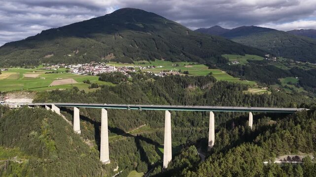 Drone aerial view of the Europa Bridge on the Brenner Autobahn near Innsbruck, Austria, spanning the Wipptal valley with alpine scenery and major transport infrastructure.