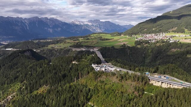 Drone aerial view of the Europa Bridge on the Brenner Autobahn near Innsbruck, Austria, spanning the Wipptal valley with alpine scenery and major transport infrastructure.