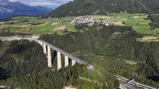 Drone aerial view of the Europa Bridge on the Brenner Autobahn near Innsbruck, Austria, spanning the Wipptal valley with alpine scenery and major transport infrastructure.