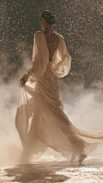 Female model spraying perfume into the air, fine mist glowing in warm light, soft draped fabric, elegant beauty styling and luxury fragrance mood.