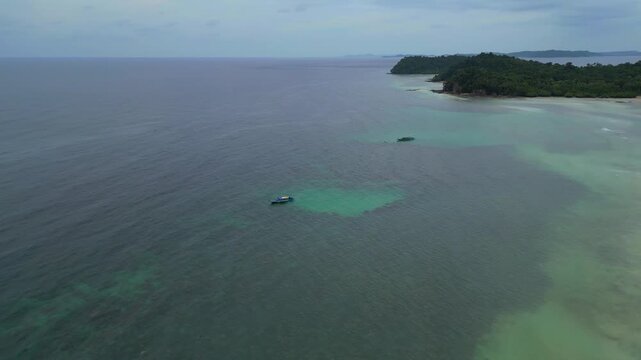 Aerial view of Batam Island coastline with small boats anchored in clear turquoise water off the coast of Batam, Riau Islands, Indonesia.
