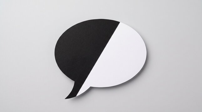 A single split black and white paper speech bubble shape placed against a neutral grey background representing communication and duality