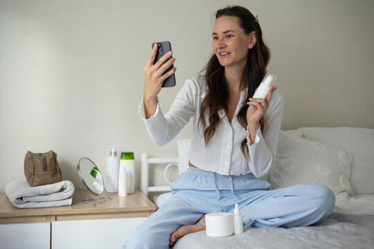 Woman filming a beauty blog about skincare products and cosmetics during a home beauty routine