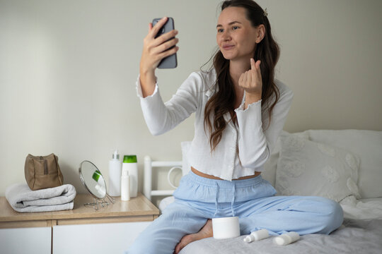 Woman filming a beauty blog about skincare products and cosmetics during a home beauty routine