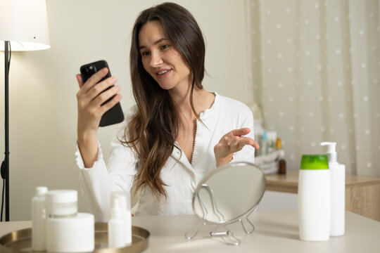Woman filming a beauty blog about skincare products and cosmetics during a home beauty routine