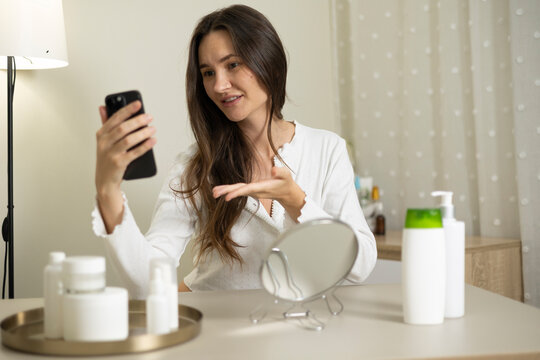 Woman filming a beauty blog about skincare products and cosmetics during a home beauty routine