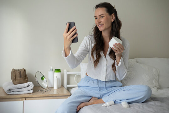 Woman filming a beauty blog about skincare products and cosmetics during a home beauty routine