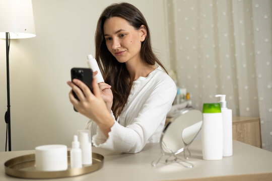 Woman filming a beauty blog about skincare products and cosmetics during a home beauty routine