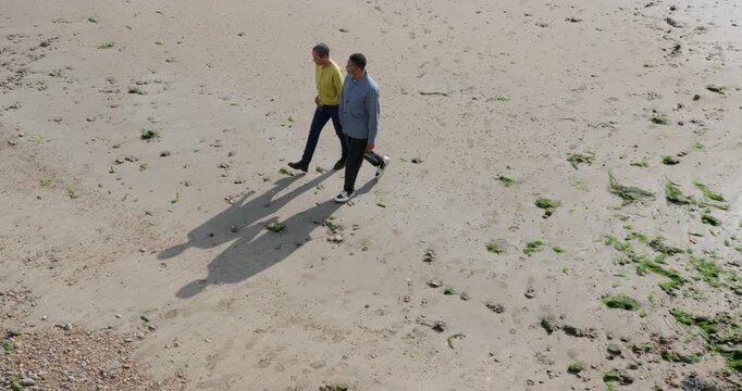 Senior Couple Walking along the beach in Autumn