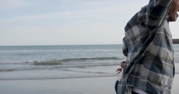 Senior Couple Running Hand in Hand by the Sea