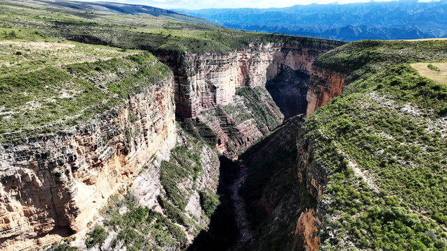 Aerial view of El Vergel canyon featuring steep rock walls, lush green vegetation on the plateau, and a deep gorge in Torotoro, Potosi Department, Bolivia.