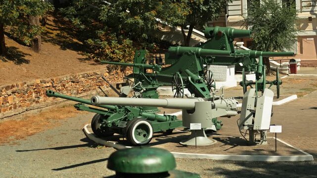 Obsolete, abandoned, and rusty combat guns stand amidst the natural landscape. A graveyard of weaponry. An echo of war.