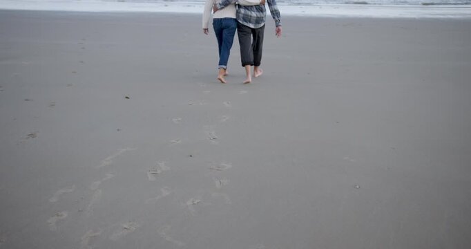 Senior Couple Embracing and  Walking Together on Beach