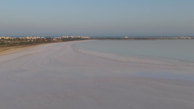 Aerial view of Larnaca Salt Lake with its expansive salt flats and calm waters under a clear sky near the city of Larnaca, Larnaca, Cyprus.