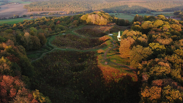 Aerial view of the World War 1 battlefield site of Vauquois Hill with deep craters, historic trenches, and dense autumn forests, Vauquois, Grand Est, France.
