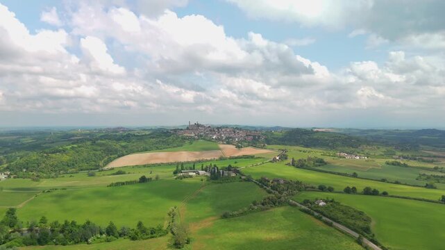 Aerial drone view of rolling green hills and a hilltop village in the Monferrato countryside, Piedmont, Italy