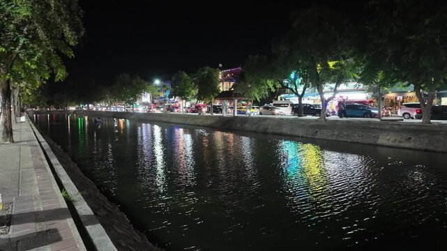 Rippling moat water reflecting city lights at night in Chiang Mai
