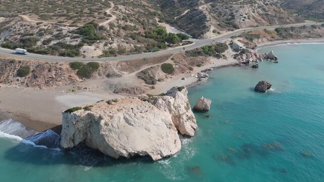 Aerial view of Aphrodite's Rock featuring turquoise waters, rocky cliffs, and a coastal road in Paphos, Cyprus.