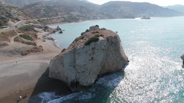 Aerial view of the iconic Aphrodite's Rock formation rising from the turquoise Mediterranean waters along the rugged coastline of Paphos, Cyprus.