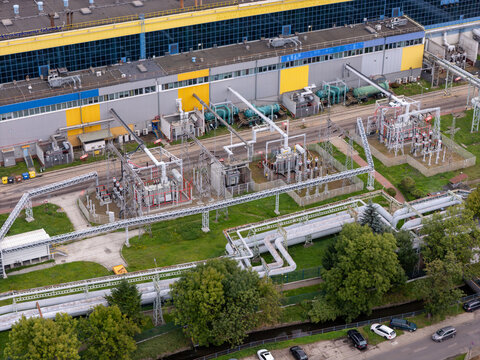 Aerial view of the coal-fired power plant featuring industrial pipelines, electrical transformers, and a large building with yellow and blue panels in Gdansk, Poland.