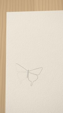Watercolor butterfly drawn on paper comes to life and flies off the page, pencil sketch to painted illustration, vertical video seamless loop