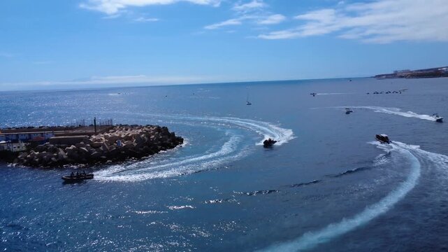 Vista con dron de lanchas r&aacute;pidas dejando estelas blancas en el Atl&aacute;ntico azul junto al rompeolas de un puerto, Costa Adeje, Tenerife, Islas Canarias