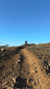 El ciclista est&aacute; subiendo el cerro con gran esfuerzo en una zona r&uacute;stica de la isla de Margarita, Venezuela.