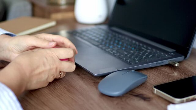 Woman squeezing pink squishy stress toy and then working on laptop using computer mouse in real time 4k footage. Concept of multitasking, work stress relief and tactile coping during digital tasks.