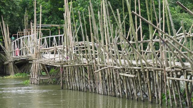 People crossing a traditional bamboo bridge