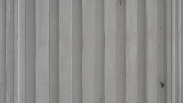 Close-up of a white painted wall with vertical raised panels and subtle surface texture.