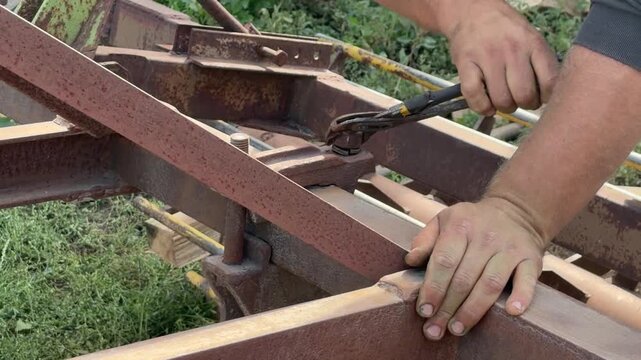 Adjustable wrench turning a nut on a rusty steel frame