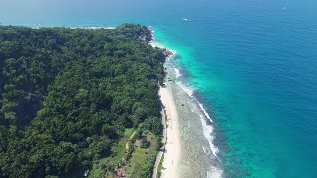 Aerial view of Anse Reunion beach with turquoise water, white sand, and lush tropical forest along the coast of Anse Reunion, La Digue, Seychelles.