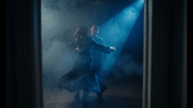 Person dancing in ethereal light through glass doorway, surreal blue atmosphere
