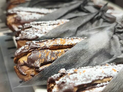 Chocolate topped pastries with powdered sugar displayed in paper sleeves
