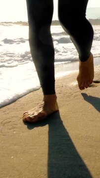 Athletic woman walking along the beach after her workout. Vertical video.